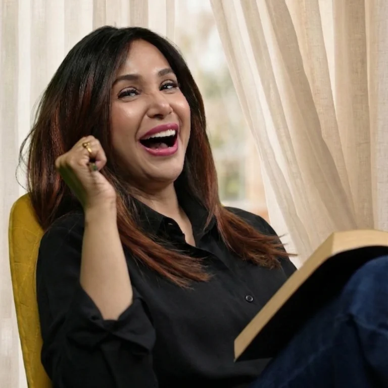Indian actress and famous book writer Preeti Mallapurkar wearing a black outfit & sitting with a notebook book & a pen writing down her ideas for her upcoming book, she looks very happy a deep smile full of enjoyment out of writing down her ideas.
