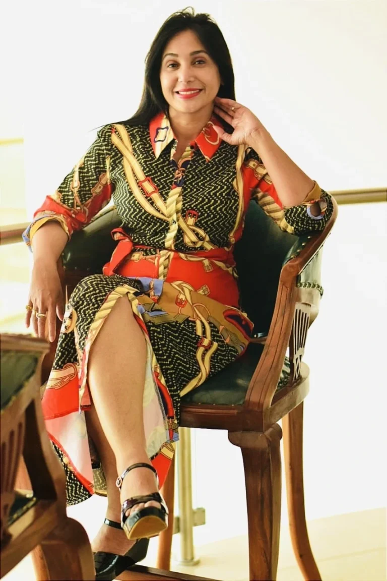 Preeti Mallapurkar sitting in a traditional wooden chair, wearing a beautifully designed dress.