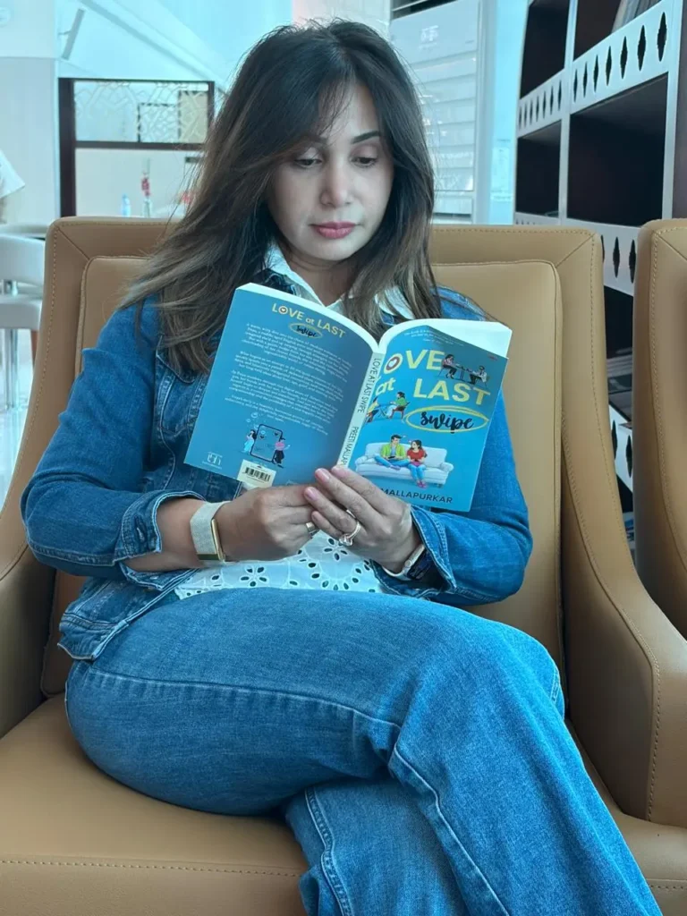 Indian Marathi actress Preeti Mallapurkar sitting on a sofa and reading her own book "Love at Last Swipe".