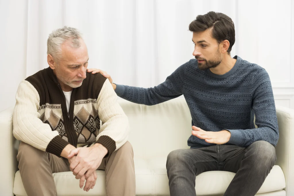 young guy with hand shoulder aged sad man sofa